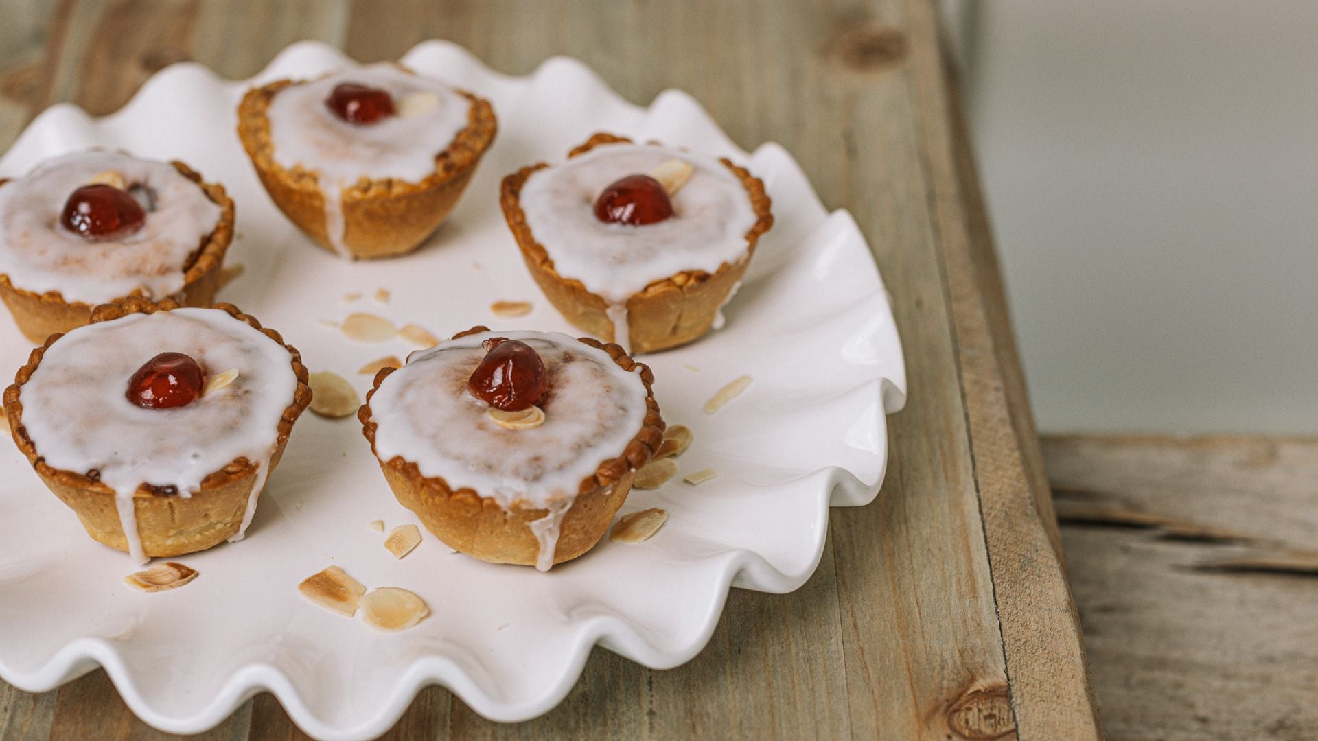 Cherry bakewell tarts on frilly white plate.
