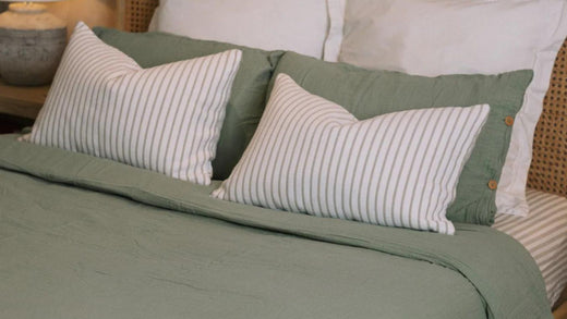 Sage green home accessories, bed spread with white pillows.