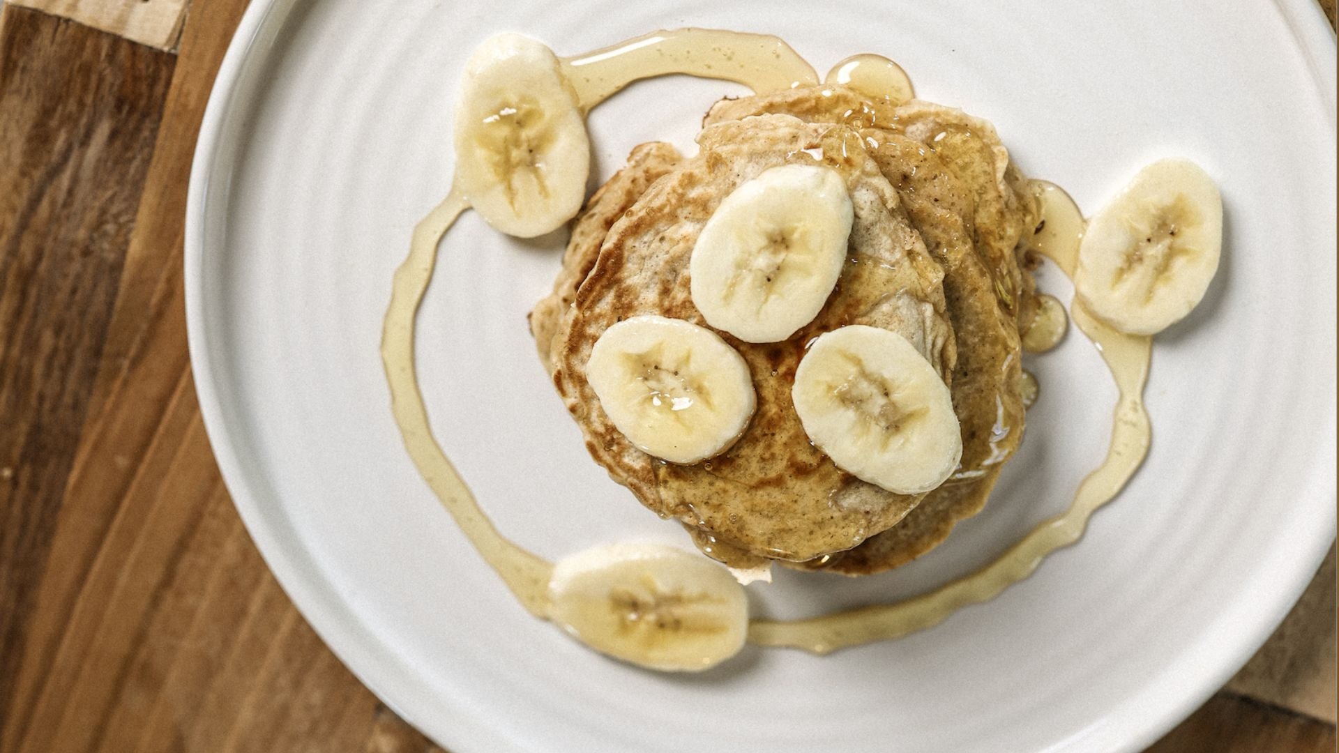 Stack of pancakes with bananas and honey.