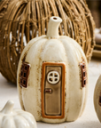 Pumpkin shaped ceramic tea light holder on table with other fall decorations.