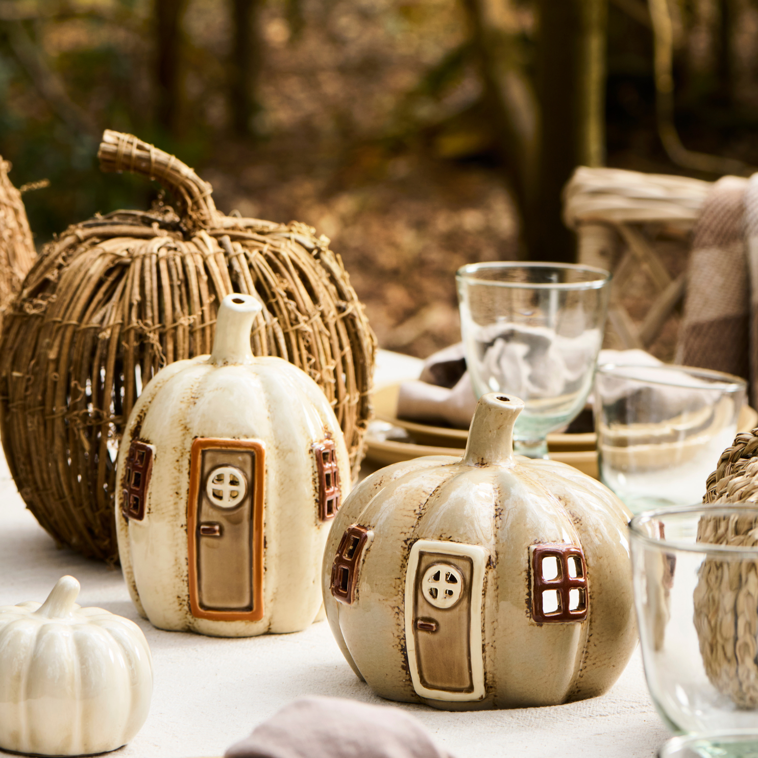 Ceramic pumpkin tea light holder on table with other fall decorations.