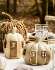 Ceramic pumpkin tea light holder on table with other fall decorations.