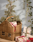 Woven basket with handle with Christmas presents and small tree.