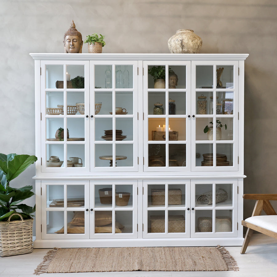 Large white armoire cabinet with glass doors filled with home decor.