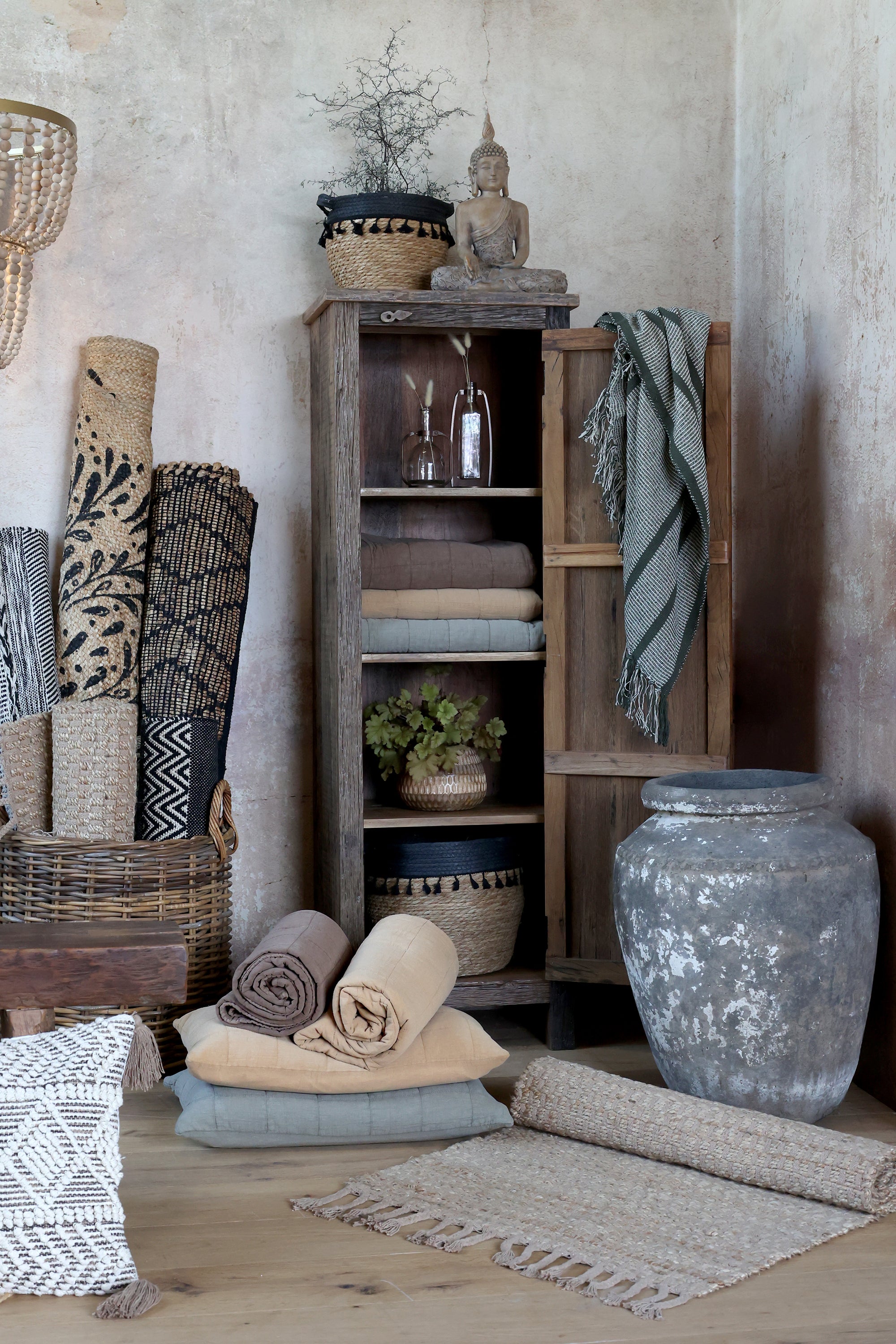 Tall reclaimed wooden with the door open, filled with textiles, blankets and plants.