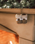 Hanging decoration of brown and white furry booties on stone fireplace with garland.