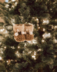 Hanging decoration of brown and white furry booties on Christmas Tree with lights.