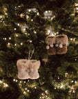 Hanging decoration of brown and white furry booties on Christmas Tree with lights.