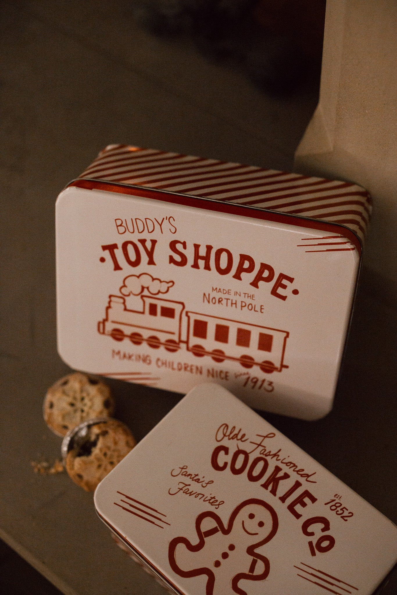 Set of two Christmas themed red and white candy cane storage tins on stone fireplace with a mince pie.