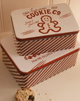 Set of two Christmas themed red and white candy cane storage tins on a white shelf with a mince pie.