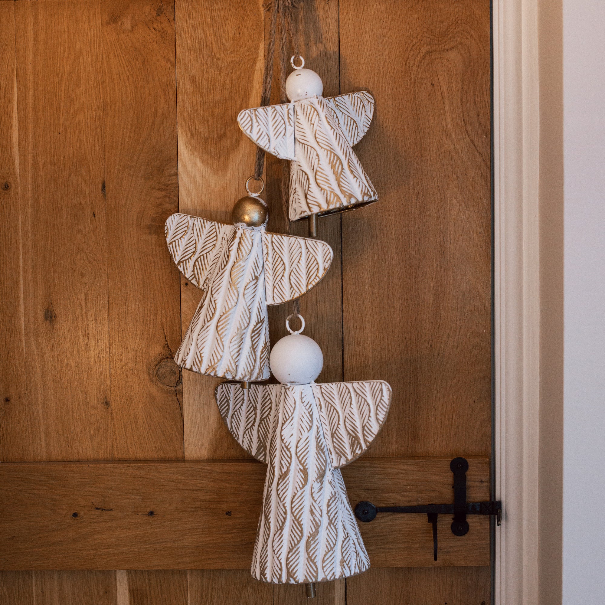 White and gold christmas angels hanging decoration on wooden door.