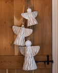 White and gold christmas angels hanging decoration on wooden door.