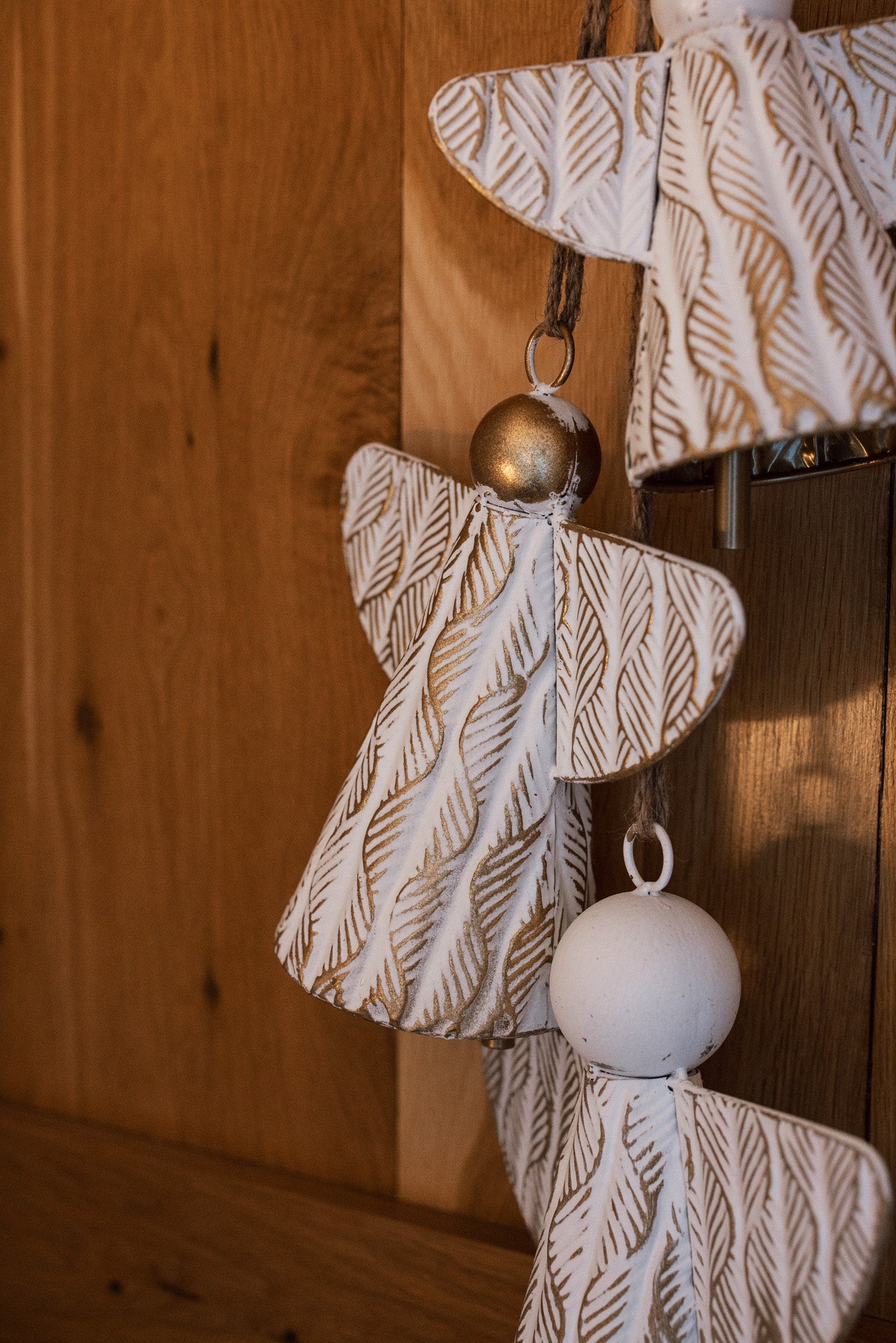 White and gold christmas angels hanging decoration on wooden door.