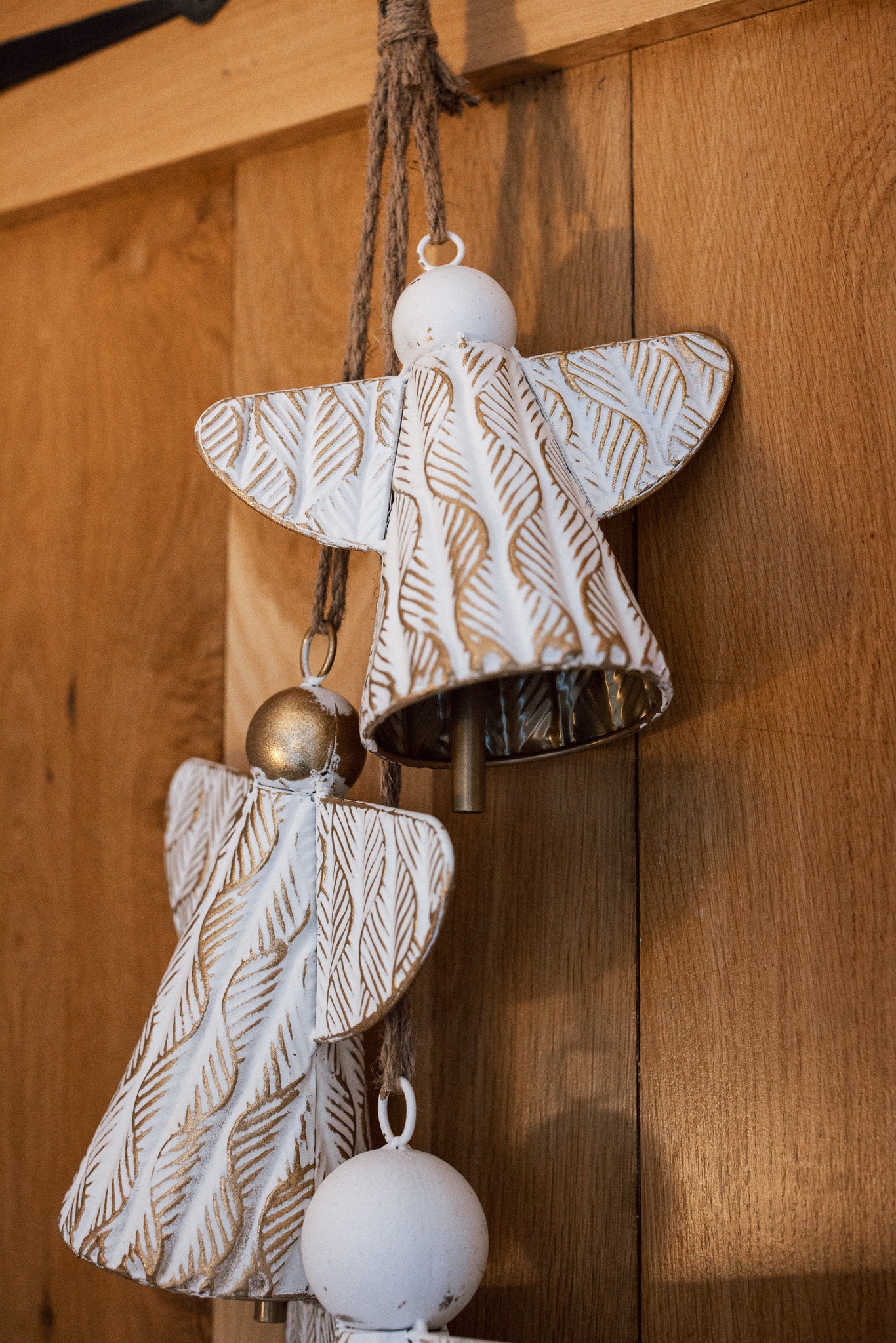 White and gold christmas angels hanging decoration on wooden door.