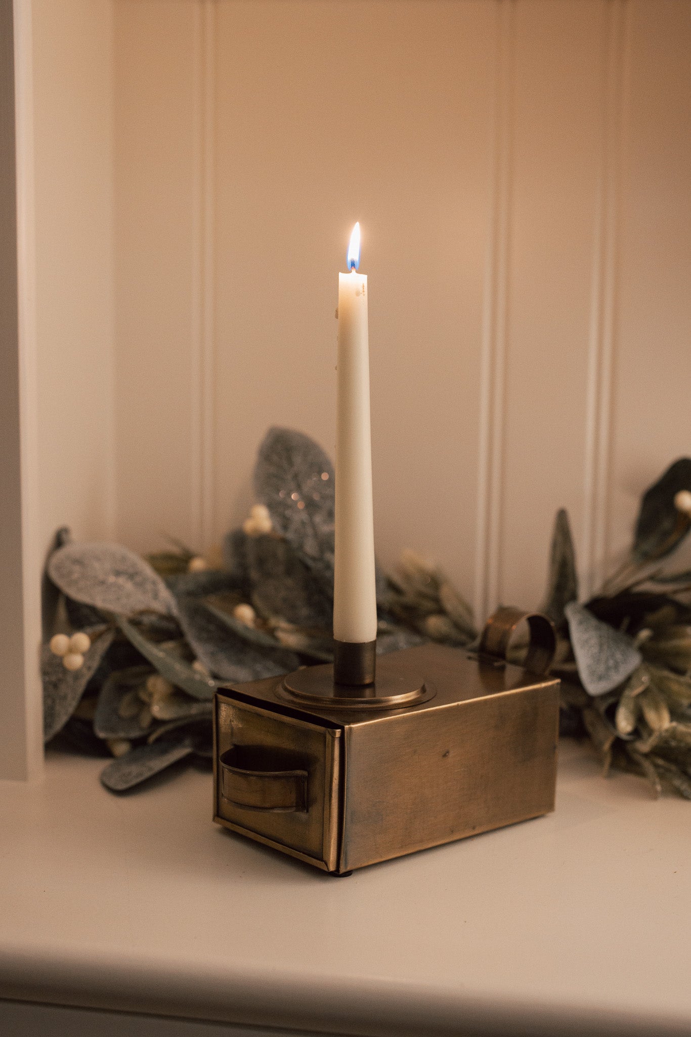 Antique Brass Candle Holder With Drawer and matches on white cabinet.