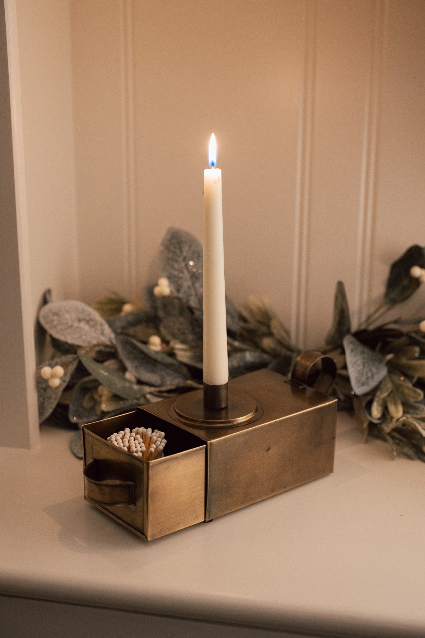 Antique Brass Candle Holder With Drawer and matches on white cabinet.