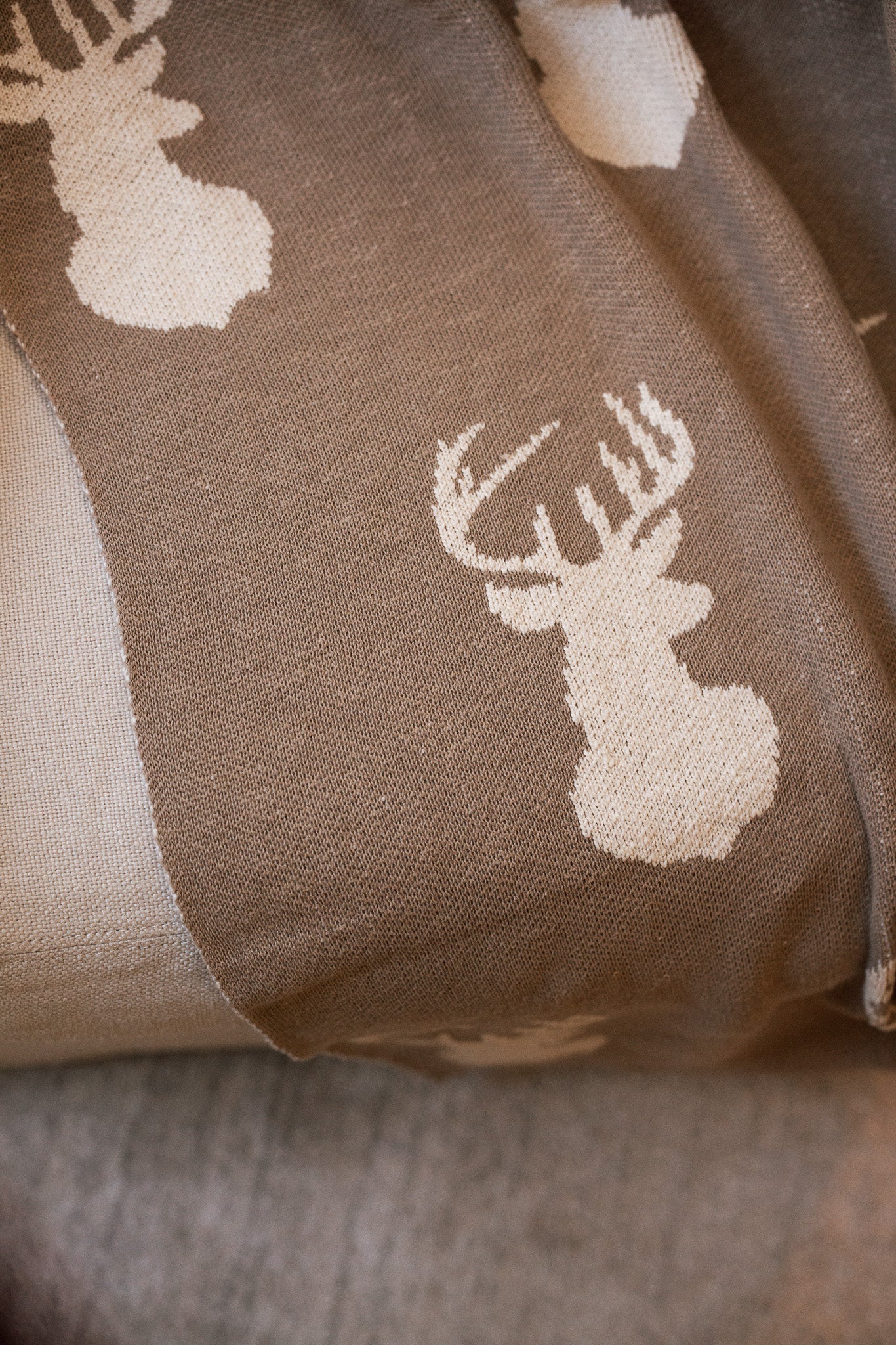 Close Up of Brown Christmas throw with cream stag head design on armchair.