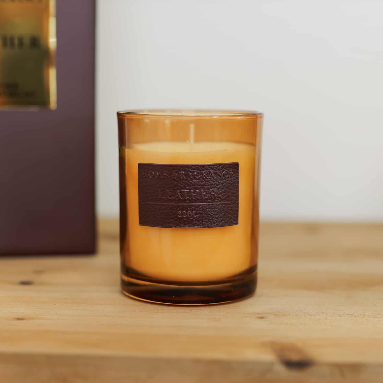 Vintage Leather Candle in orange jar on wooden console.