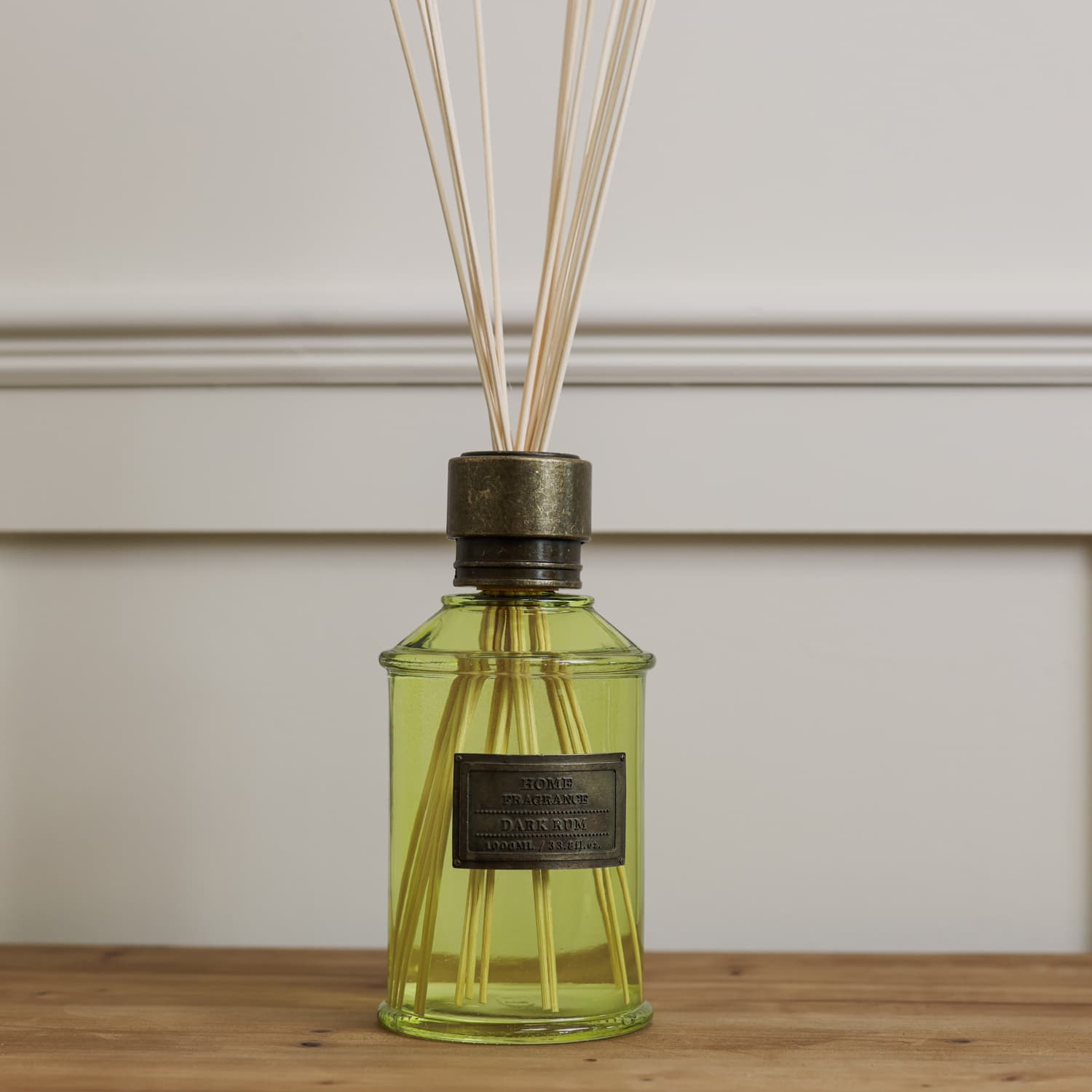 Home fragrance dark rum and lime green reed diffuser on wooden console