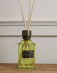 Home fragrance dark rum and lime green reed diffuser on wooden console