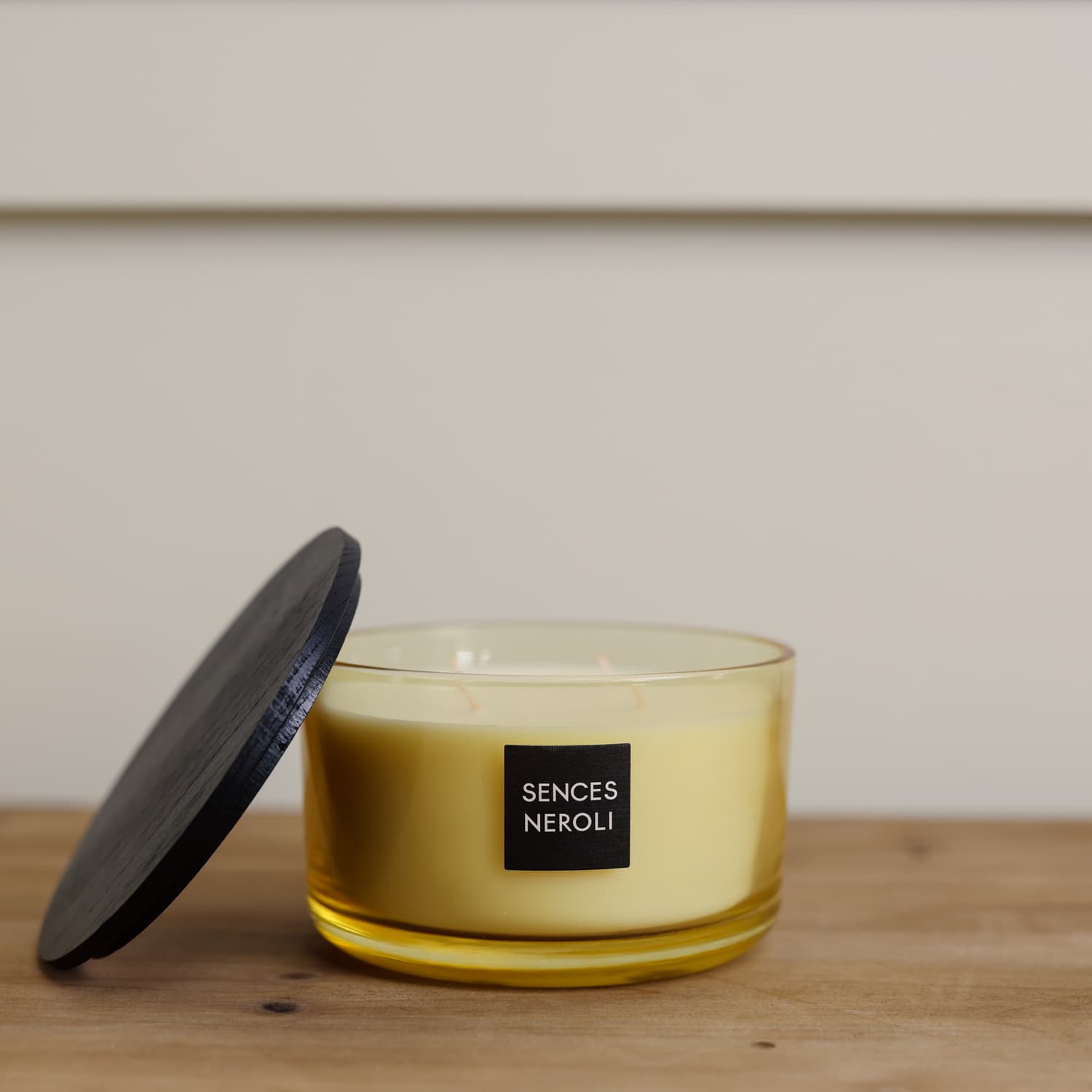 Sences Neroli Lidded Candle with lid rested on the side on wooden console.