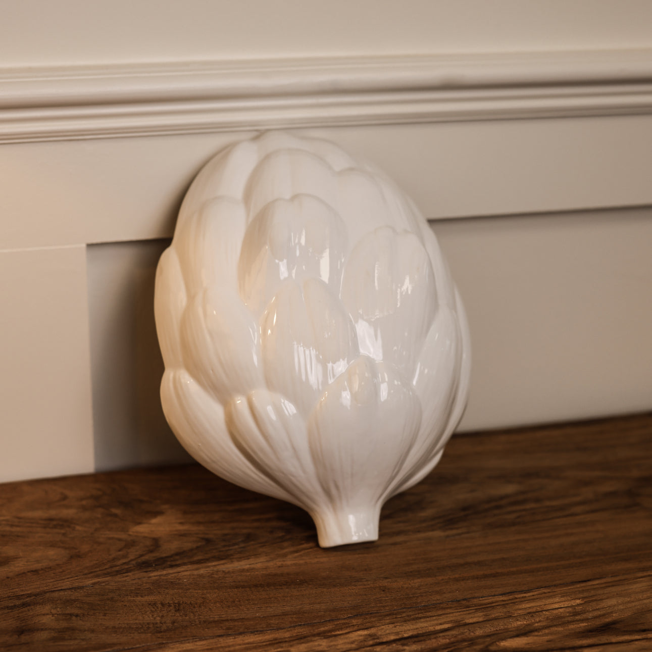 Bottom of white artichoke ceramic bowl, leaned up against a wall.