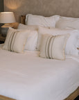 White muslin bedding set with striped cushions.