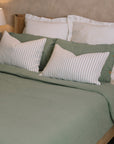 Green muslin bedding set with striped cushions.