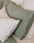 Green muslin bedding set with striped cushions.