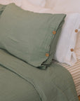 Green muslin bedding set with striped sheet.