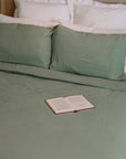 Green muslin bedding set with open book.