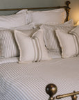 Striped neutral bedding on a brass bed.