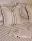 Striped neutral bedding on a brass bed with an open book.