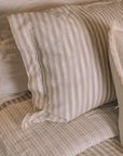 Striped neutral bedding on a brass bed.