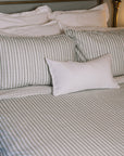 Green striped bedding on a brass bed.