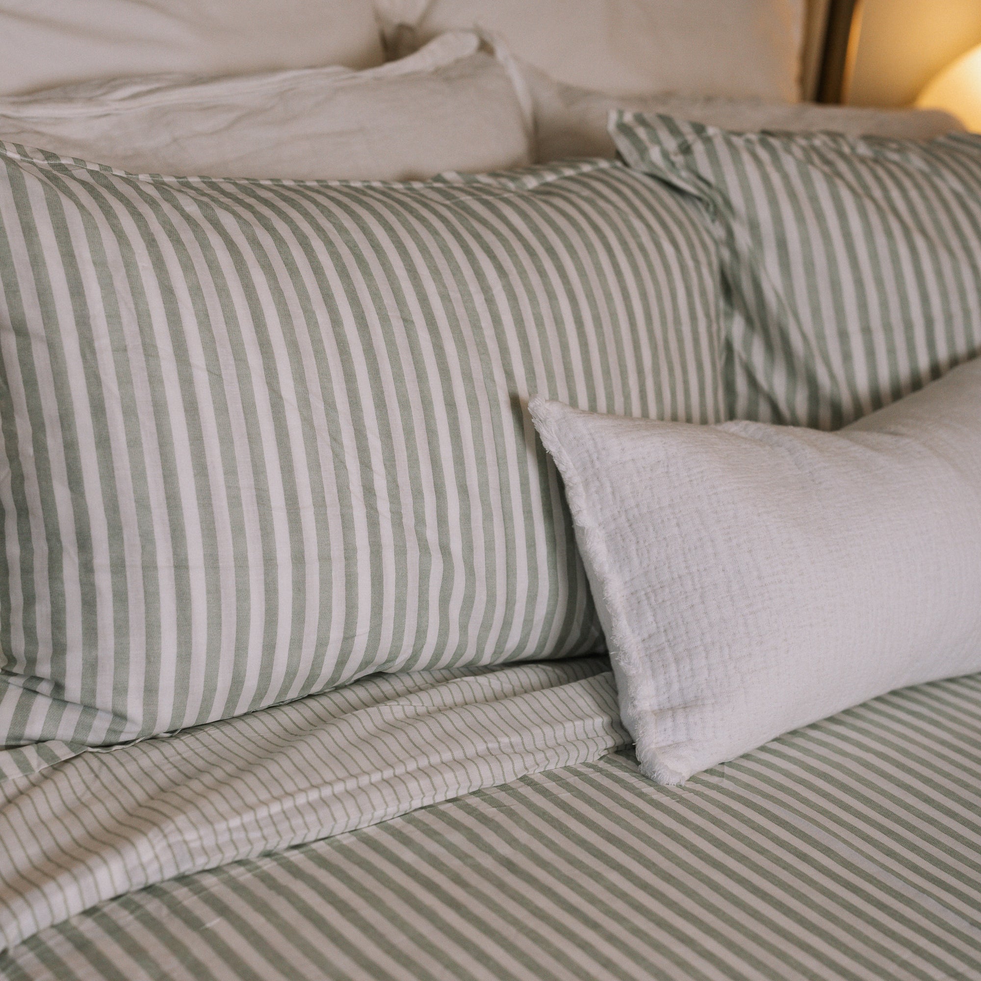 Green striped Bedding with white throw cushion.
