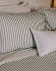 Green striped Bedding with white throw cushion.