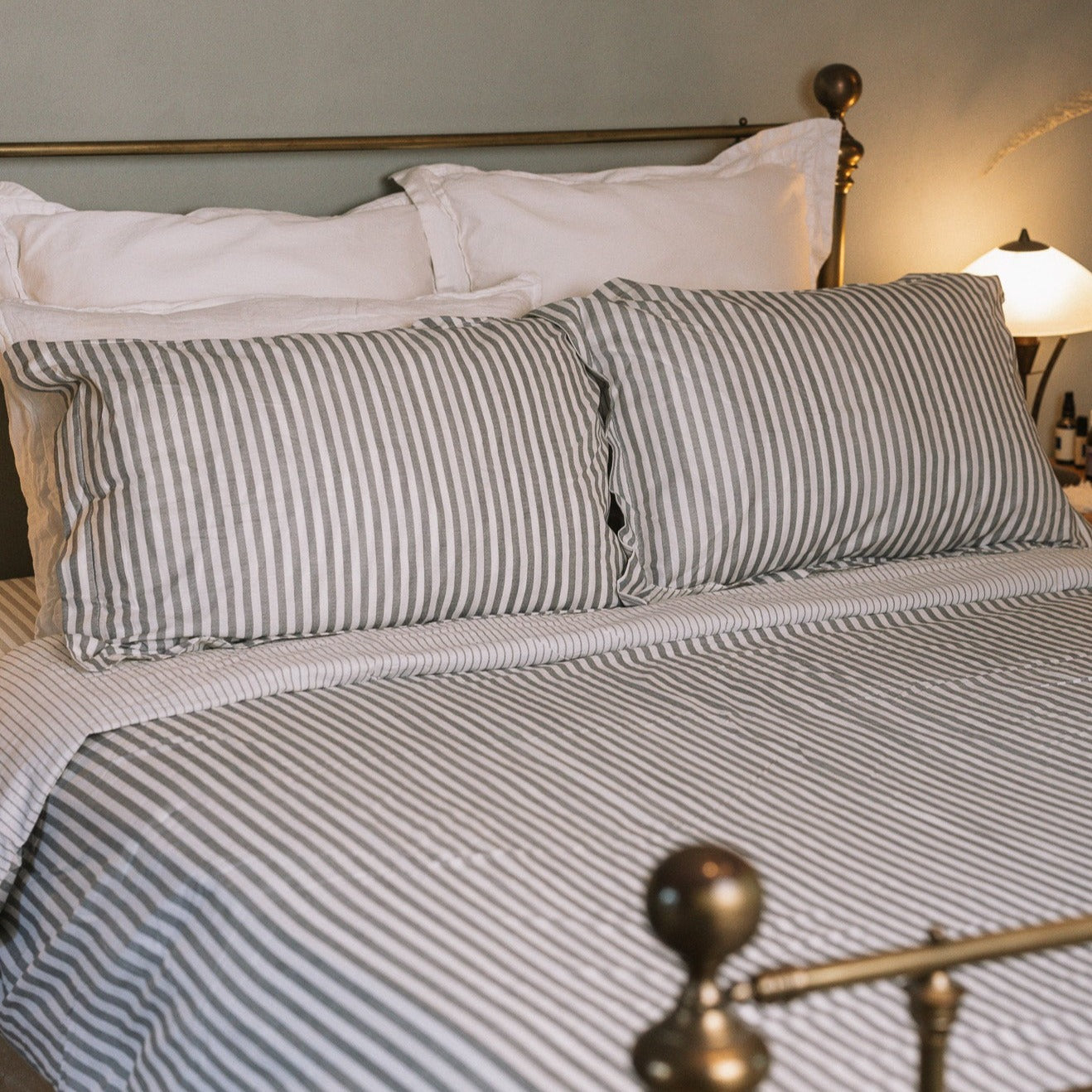Grey Striped Bedding on a brass bed.