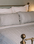 Grey Striped Bedding on a brass bed.