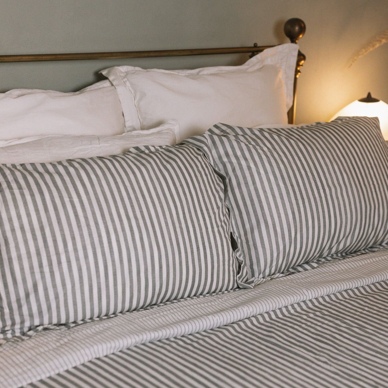 Grey Striped Bedding on a brass bed.