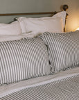 Grey Striped Bedding on a brass bed.