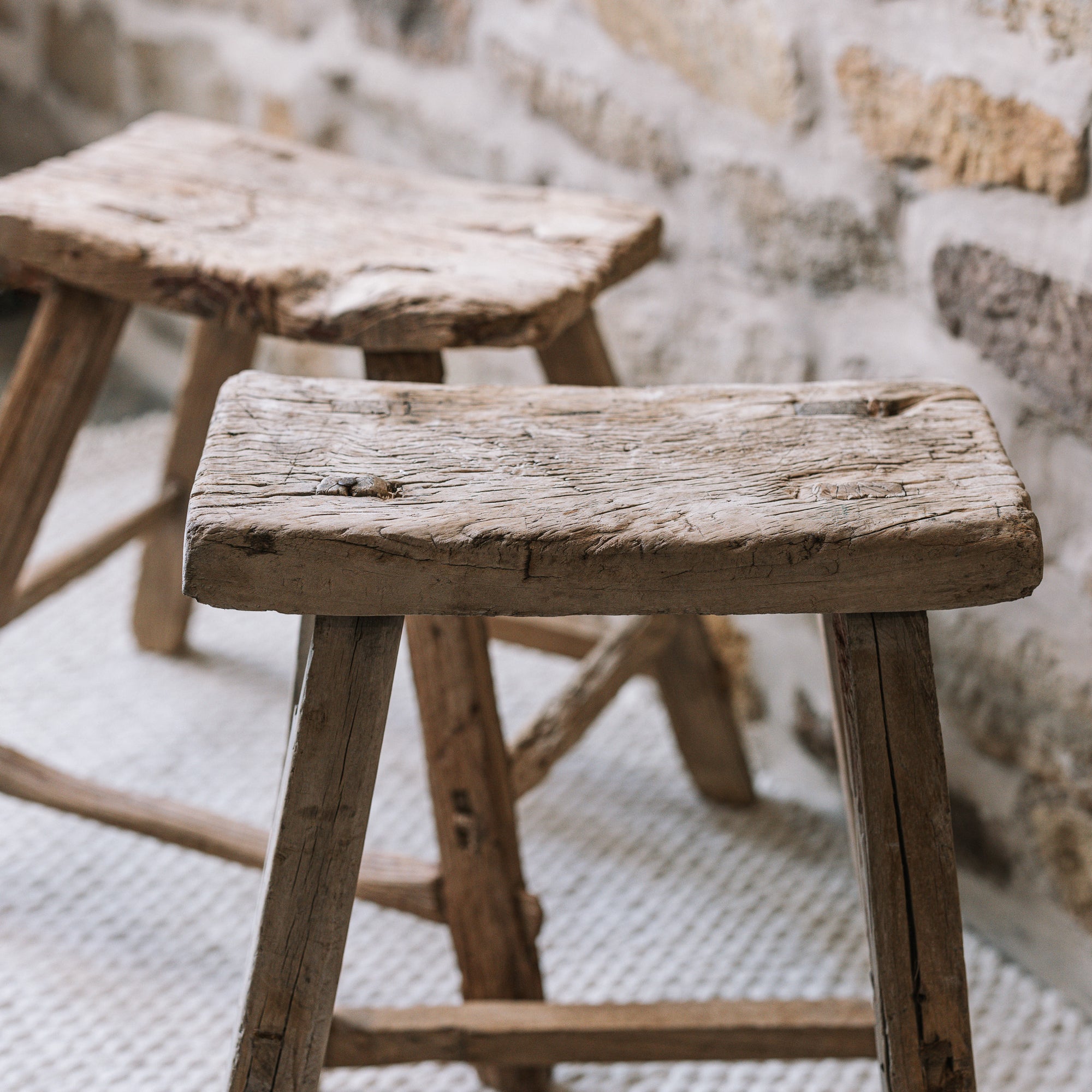 Reclaimed style wooden stools against a stone wall.