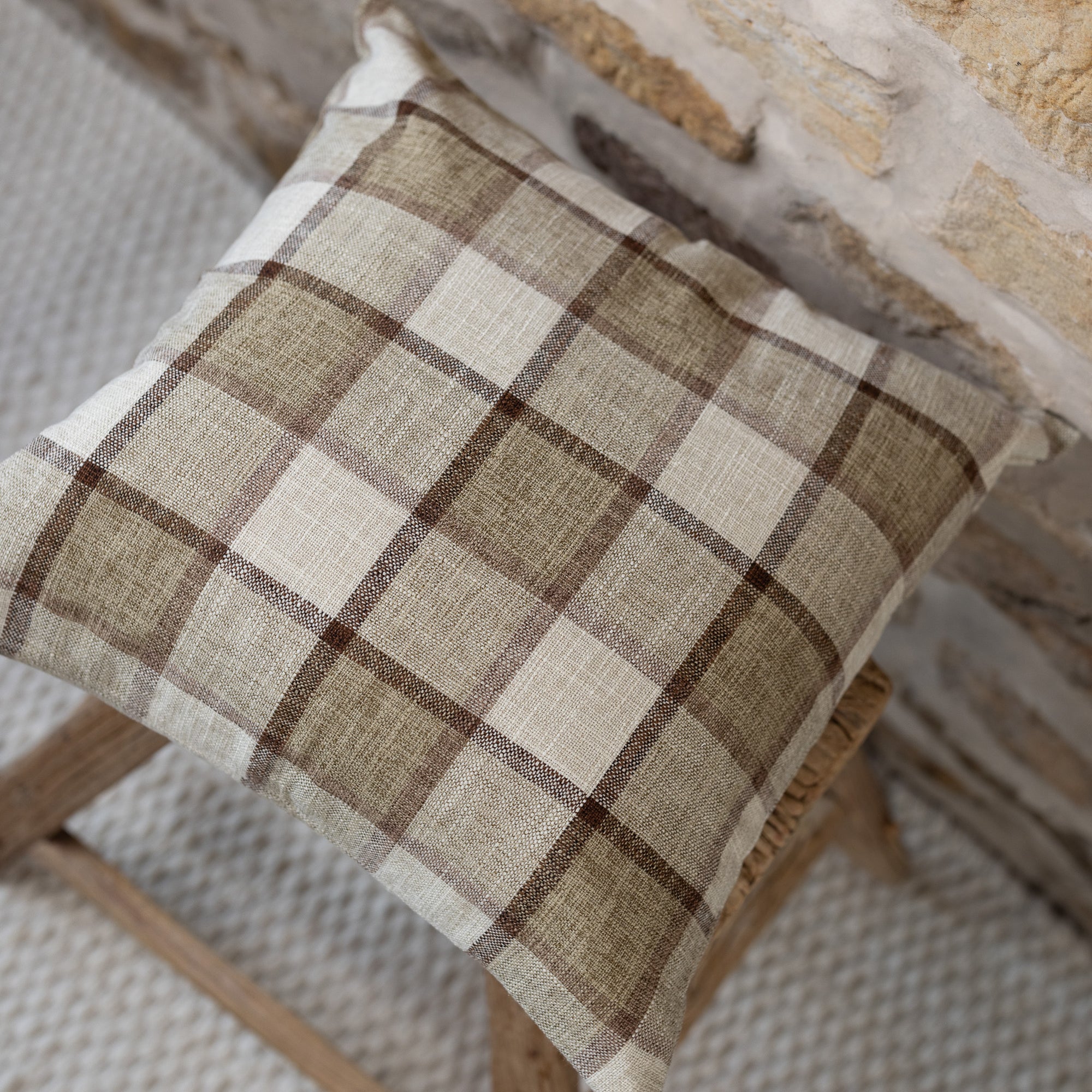 Brown and cream checkered cushion on wooden stool.
