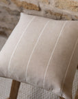 Beige and white striped cushion on a wooden stool.