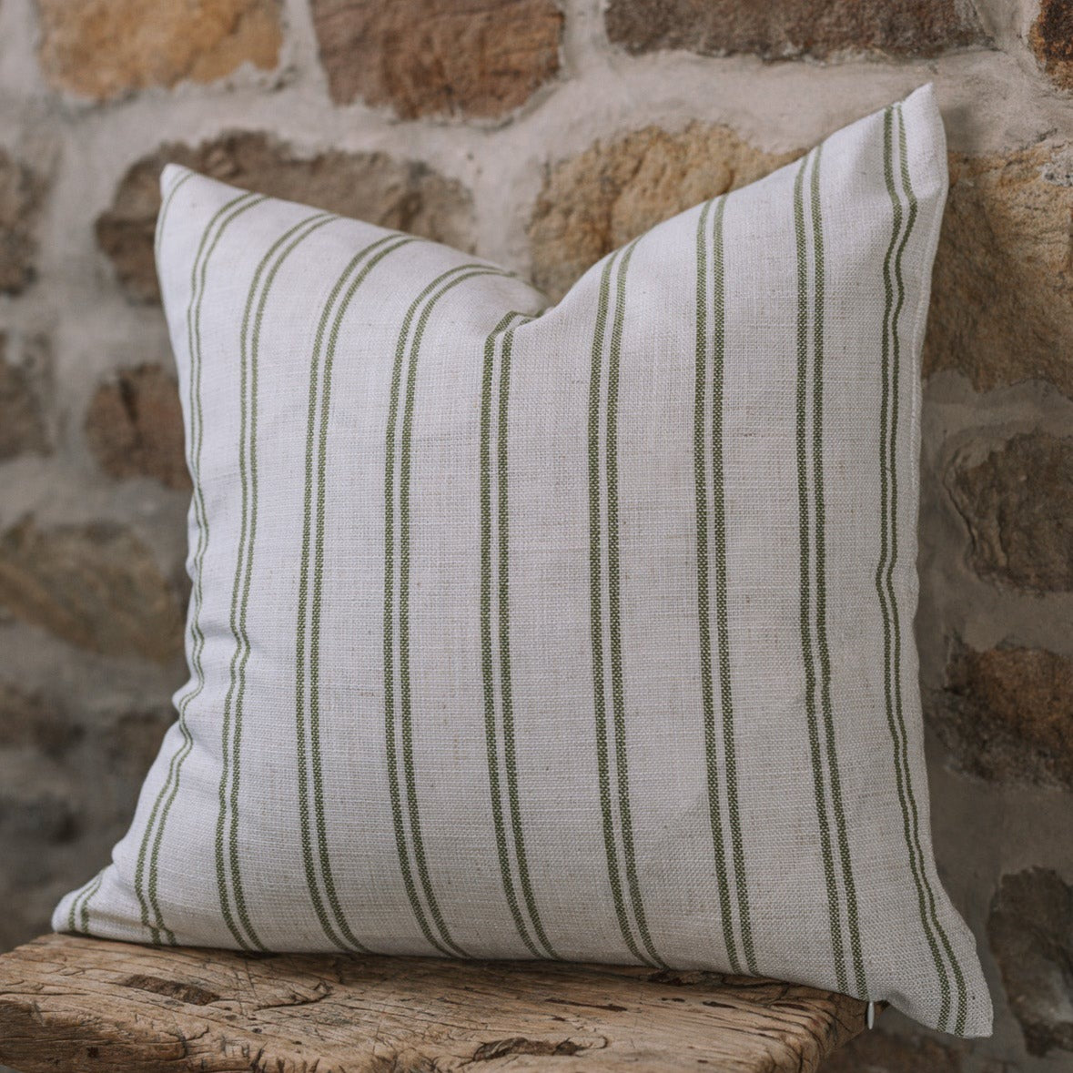 Olive and off white striped cushion on wooden stool.