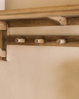 Wooden shelf with coat hooks, decorative items on shelf.