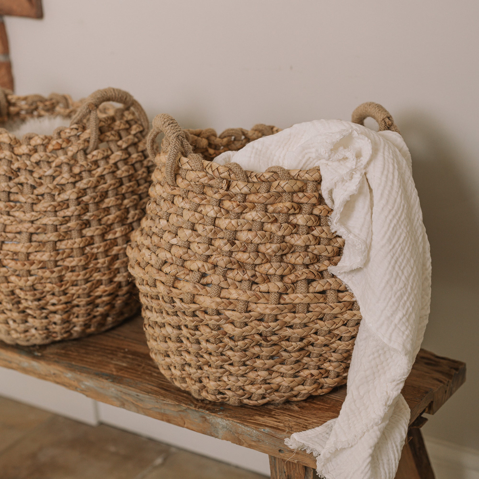 Jute woven basket with handles and a muslin blanket.