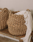 Jute woven basket with handles and a muslin blanket.