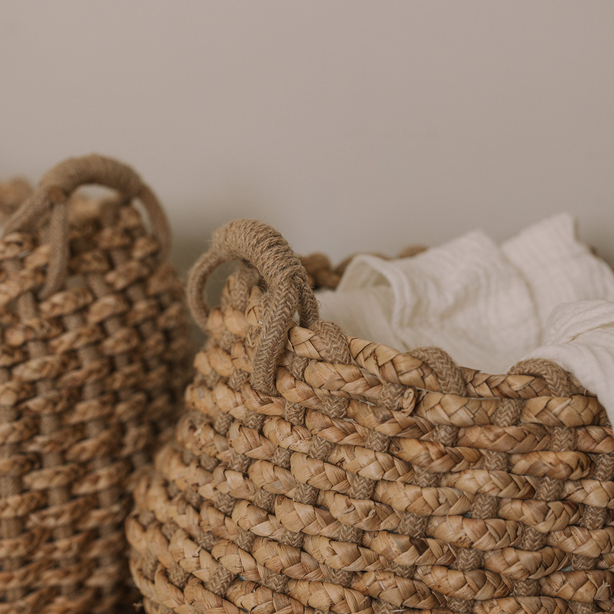 Jute woven basket with handles and a muslin blanket.