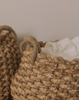 Jute woven basket with handles and a muslin blanket.